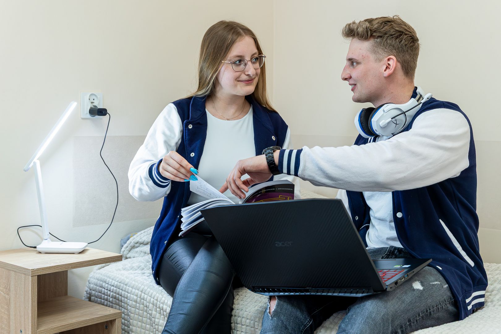 Studenci z laptopem i książką siedzący na łóżku