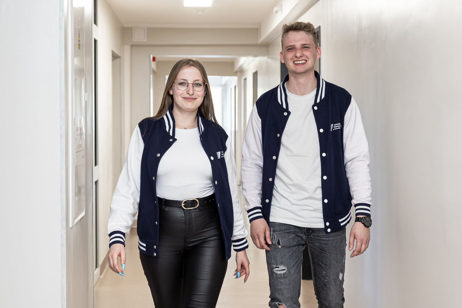 Studenci w kurtkach z logo ZUT na korytarzu w akademiku
